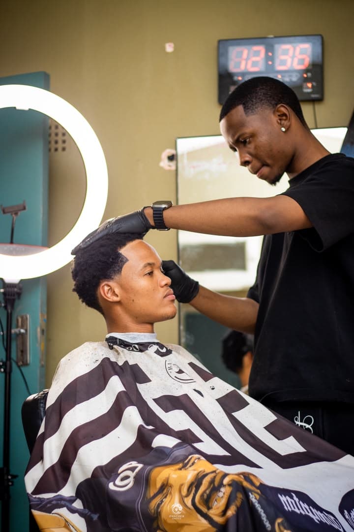 Rey The Barber shaping a client's cut under the studio ring light